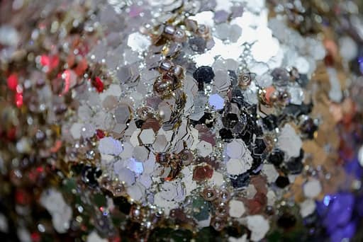 Open glass jar tipped to spill matte and iridescent sequins in coral, buttercup, sage and clear, in four sizes from tiny discs to flower shapes